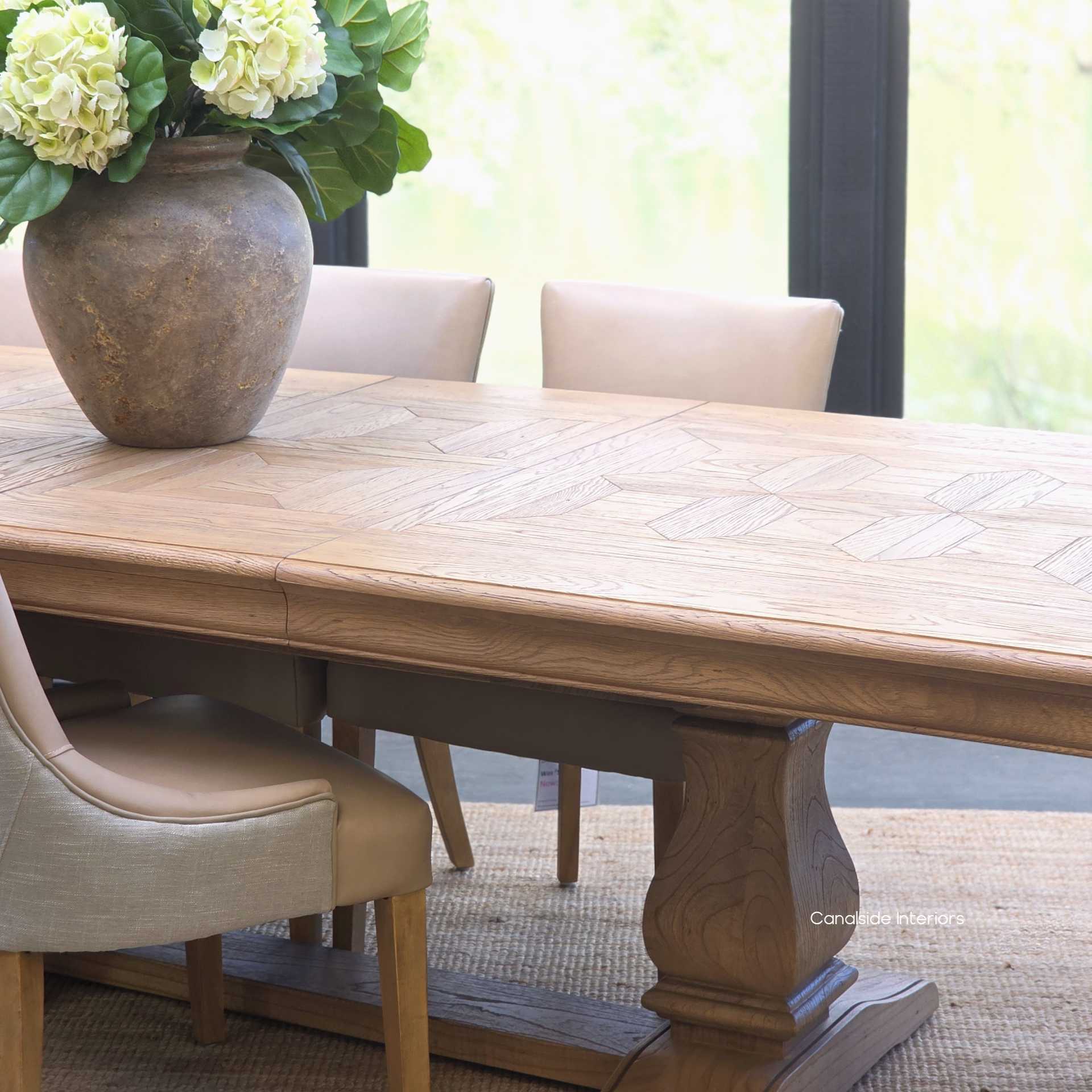 Chesterton oak parquetry dining table styled with leather and linen upholstered chairs in a timeless setting.