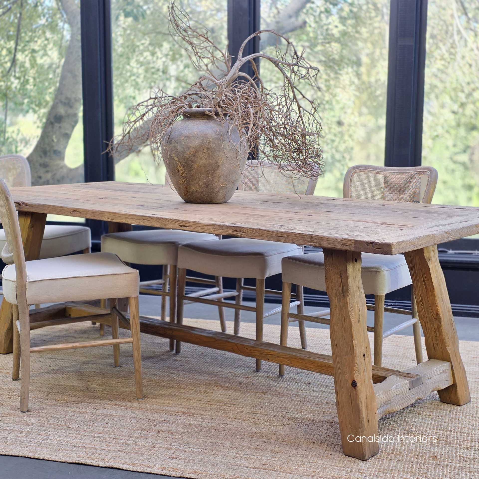 Styled table setting featuring the Hollowgrove with a large ceramic vase and woven rug beneath.