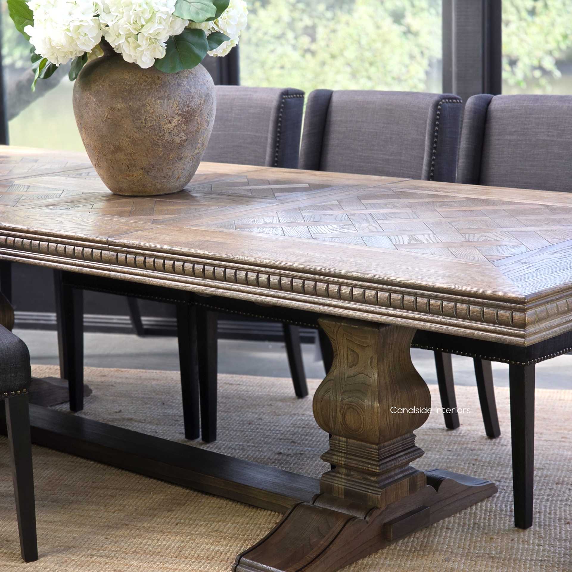 Cigar oak extendable dining table fully opened with upholstered chairs for an elegant dinner party.