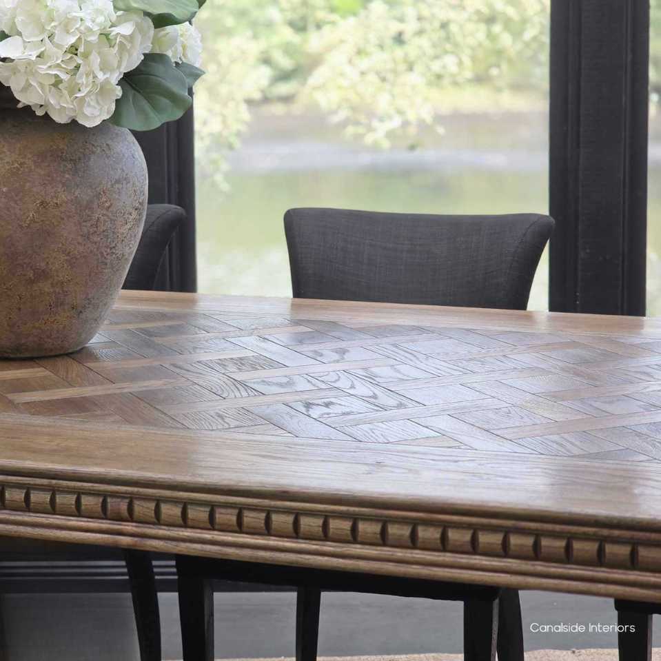 Cigar oak parquetry dining table styled with upholstered chairs for a formal dinner.