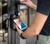 Resident tapping a phone on a LiftMaster Smart Reader to unlock a door with myQ Community - SRDRSTv2