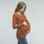 A fitted maternity top in a ribbed knit material featuring a rounded neckline, long sleeves and ruched sides.