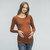 A fitted maternity top in a ribbed knit material featuring a rounded neckline, long sleeves and ruched sides.