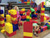 Children building tall structures with oversized, colorful plastic blocks in a play area.