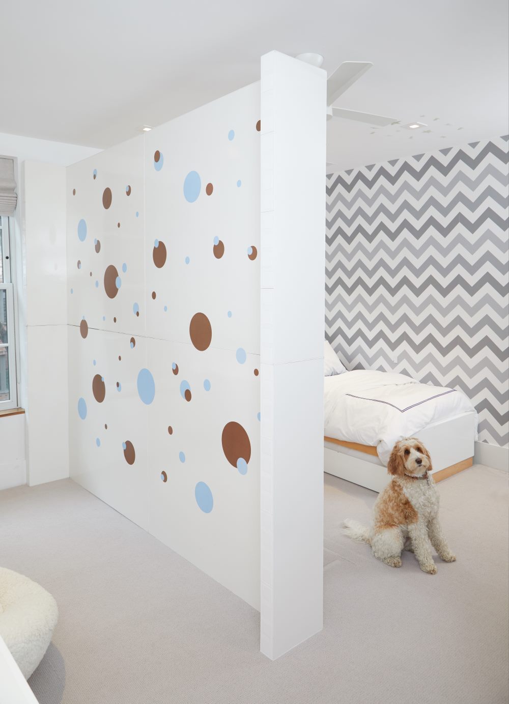 Bedroom Divided by EverPanel wall with decals attached. A bed is behind the wall and a dog next to it.