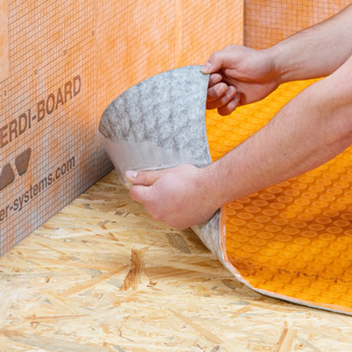 An installer peeling the peel and stick membrane on the Schluter Ditra Heat Duo PS self adhesive matting