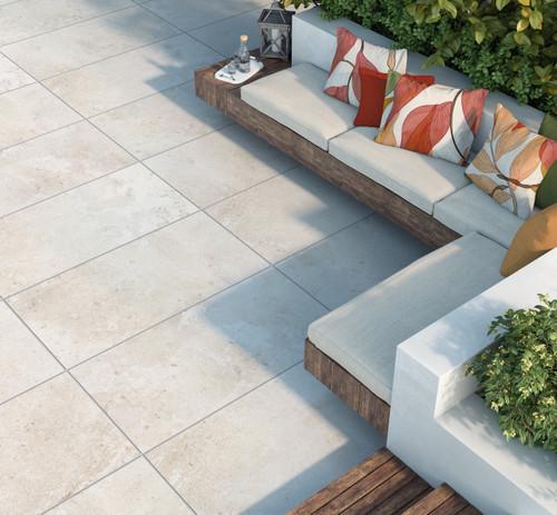 Beige travertine effect porcelain paving tiles used outdoors on a patio area with L shaped outdoor sofas