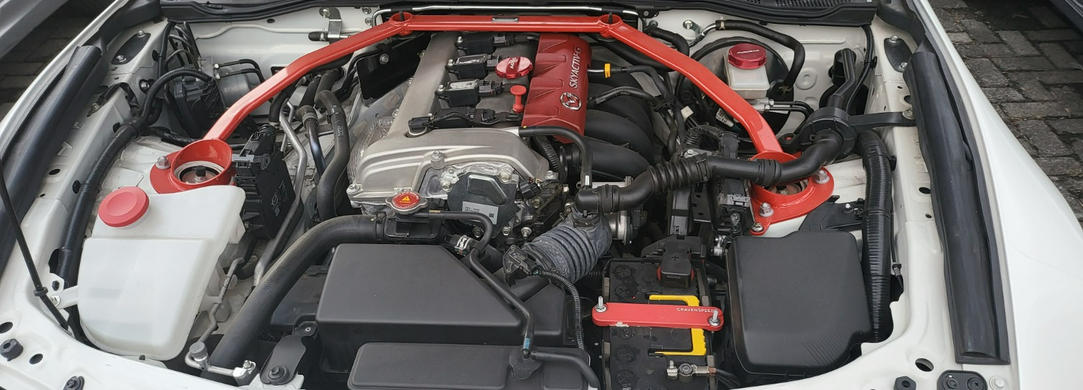 The CravenSpeed Battery Tie Down in red, installed in a 2016 ND Mazda MX-5 Miata.