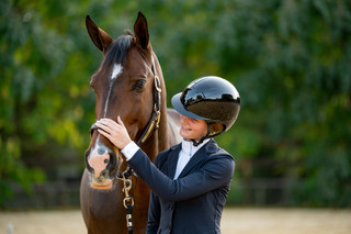 A child smiling while wearing a riding helmet