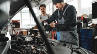 Two mechanics working on car