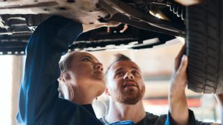 Two mechanics working on car