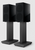 KEF R3 Meta Bookshelf Speakers in Gloss Black, with grille, on stands.

