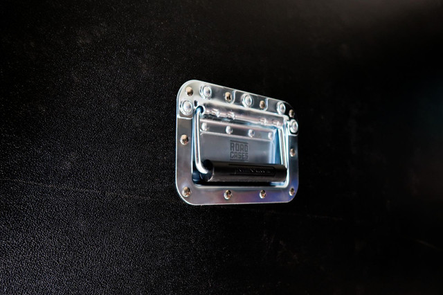 Spring-loaded handle recessed in a dished steel plate on the side of a case