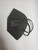 A flat lay of a black Powecom KN95 mask, showcasing its foldable, portable design.