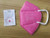 Side profile of a pink Powecom KN95 mask, showing the shape and ear loop design.