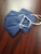 A side view of a denim blue Powecom KN95 mask, highlighting its 3D foldable design and soft ear loops. Multiple masks shown