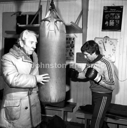 22621748-Scottish boxer Ken Buchanan in Lonsdale headgear hits the  punch-bag during a training session with his father Tommy Buchanan in March  1983