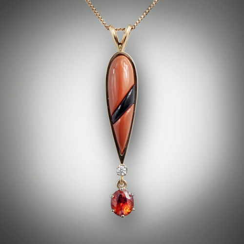 Pnd 362 has orange jasper inlay with a stripe of black jade running through the center with a 0.05 point round F color VS clarity diamond and a 7mm oval hessonite garnet all set in 14kt yellow gold.