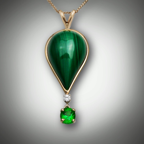 Pendant 159A Malachite is a balloon pendant with the inlay of malachite and a 3 point F/VS diamond with a dangling 5.5 by 4.5mm oval tsavorite garnet set in 14kt yellow gold.