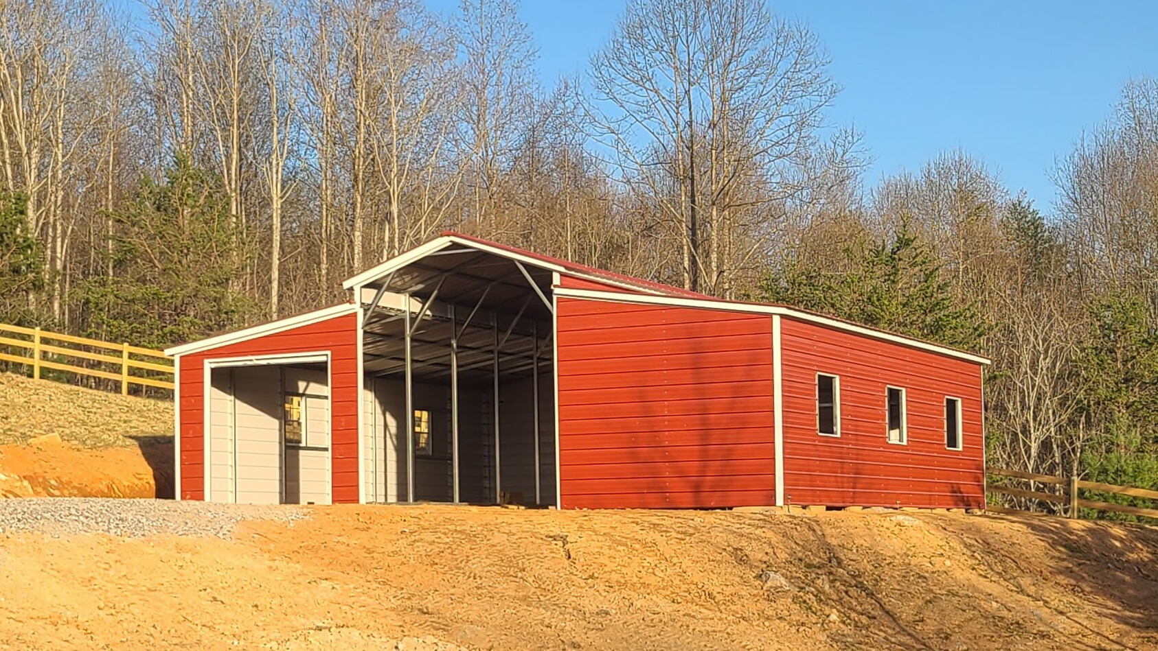 Red metal barn with a raised center aisle, open center bay, and an enclosed garage.