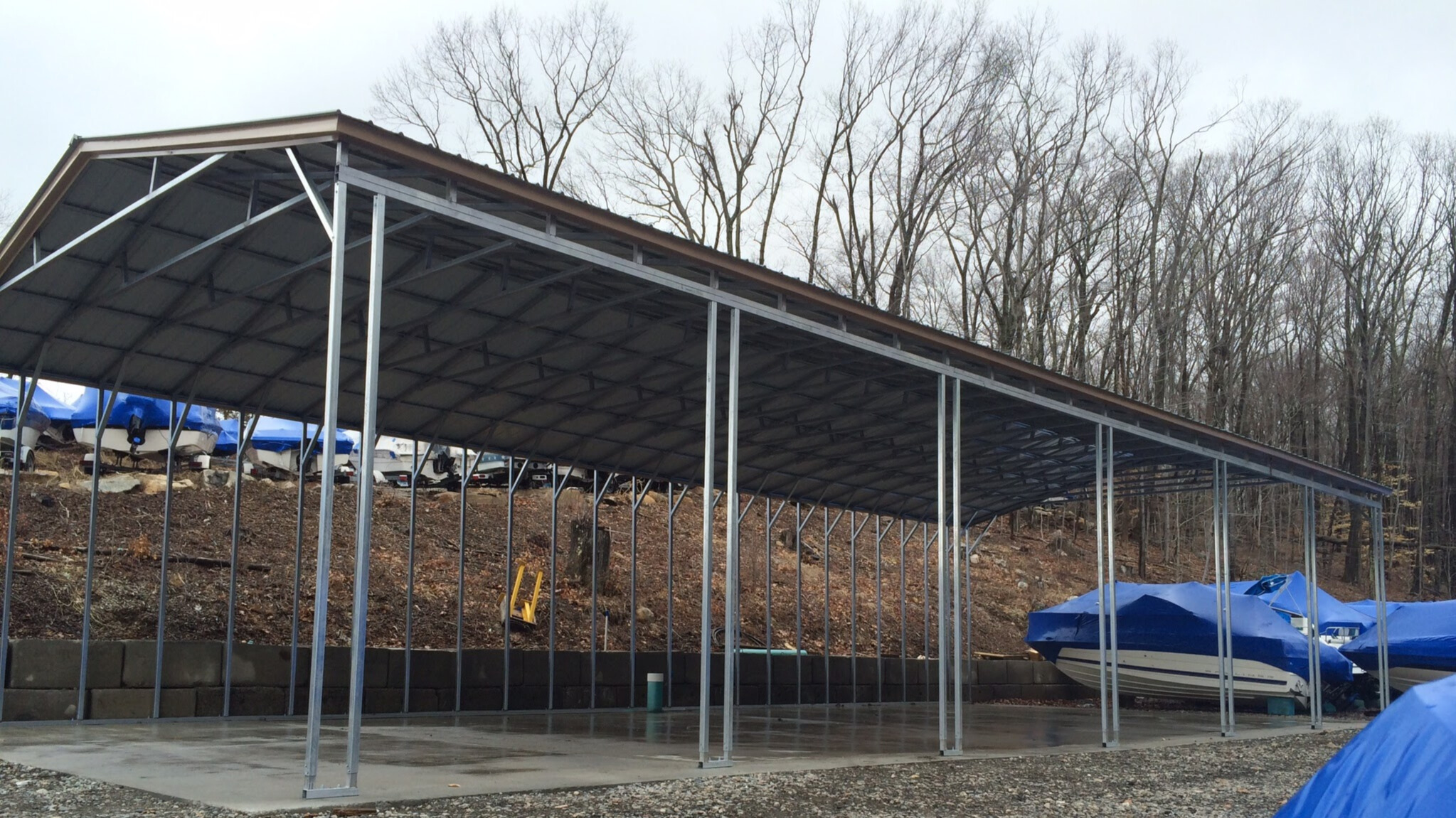 Large, open-sided steel structure used for boat storage on a concrete slab.