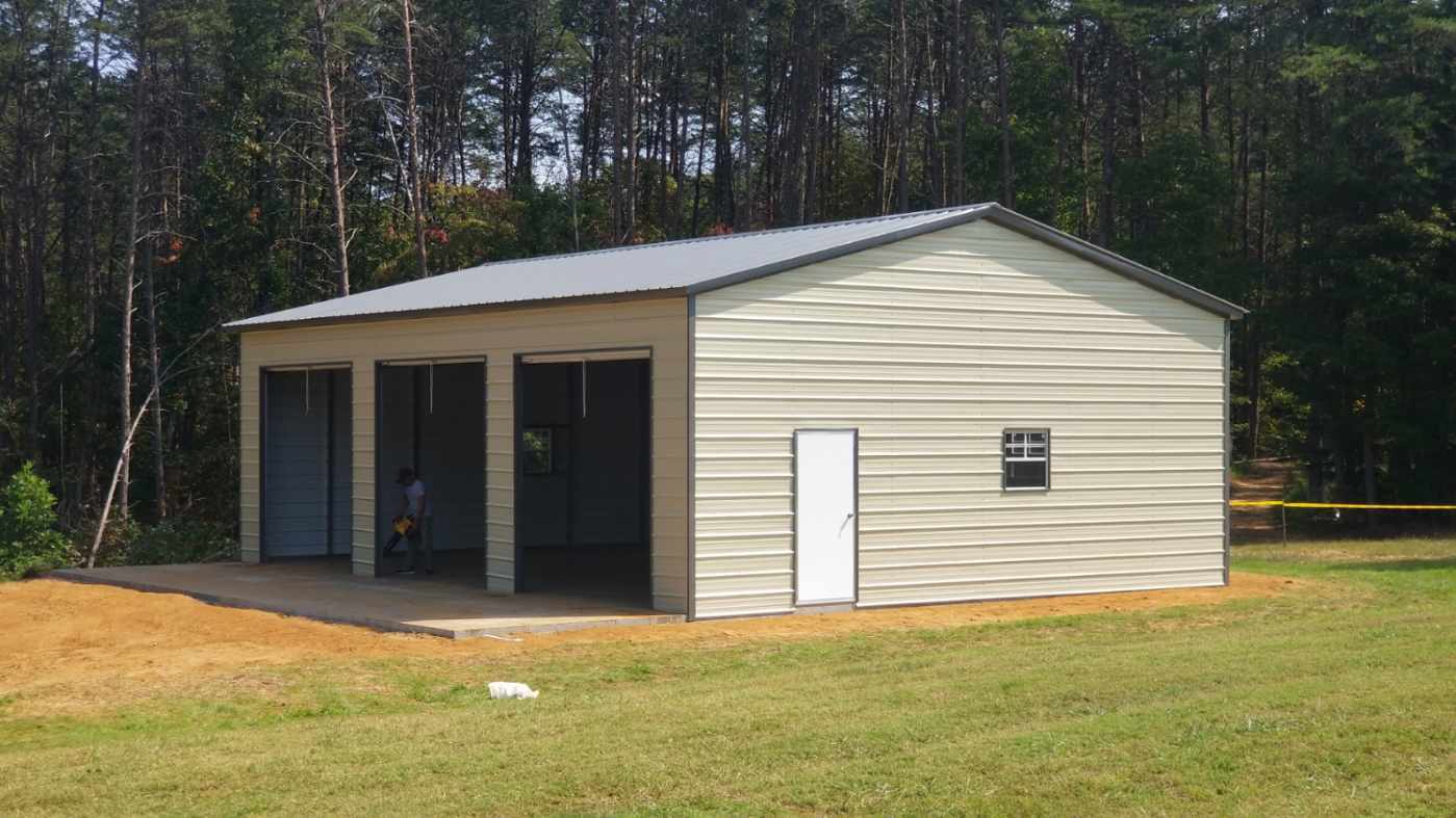 Beige three-car metal garage with three roll-up doors and a side entry door.