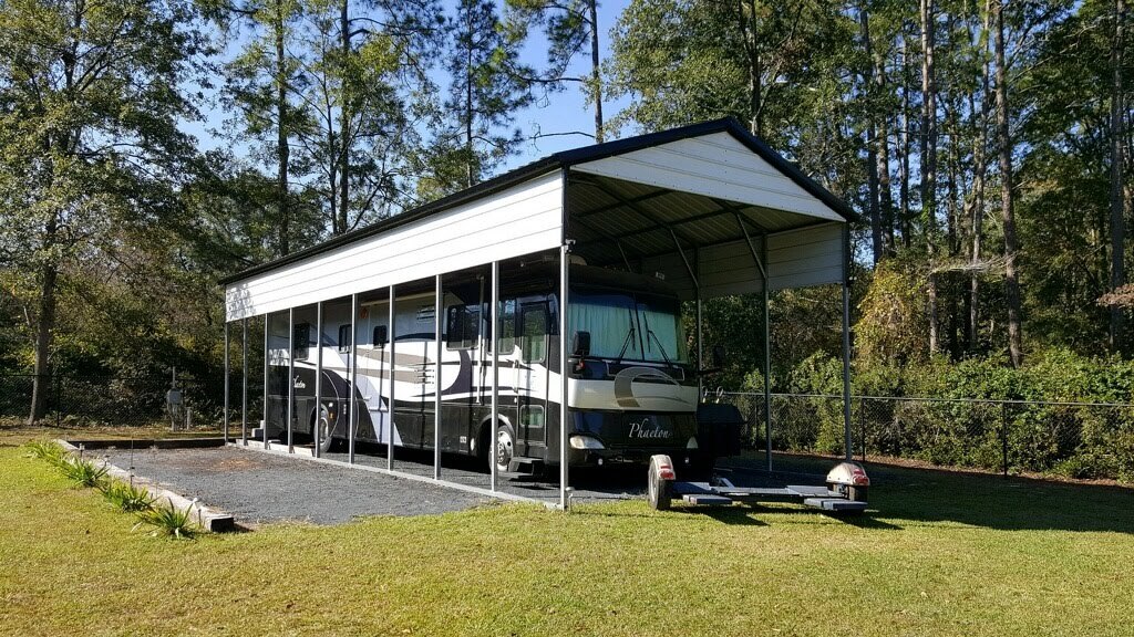 Tall white metal RV cover providing shelter for a Class A motorhome and trailer.