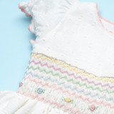 a classic smocked silhouette with delicate pastel embroidery, gathered sleeves, and a matched ric rac trim.