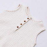 Ivory sleeveless bubble romper features a front wooden button placket and snap closures.