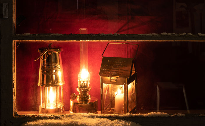 Vintage old lantern lighting in the dark forest. Travel camping concept.  Burning lantern on a moss at forest in the night. Stock Photo