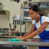 Commercial kitchen staff wiping stainless steel equipment using Foodservice quarterfold wipers