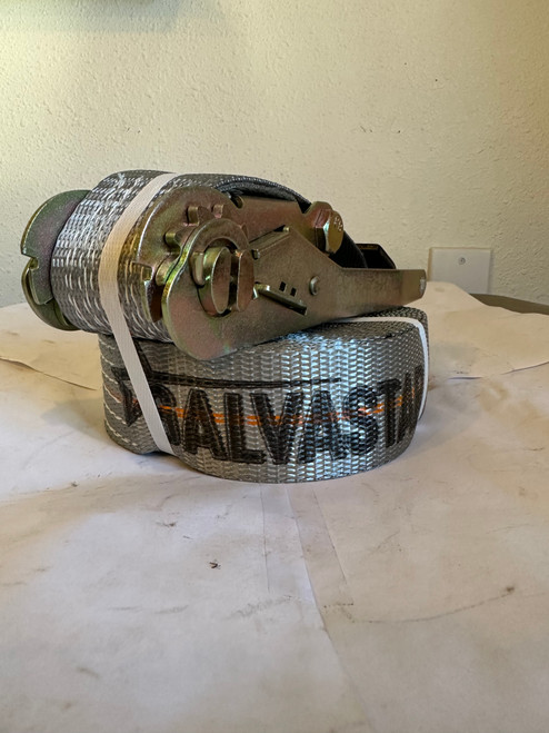 Grey 2-inch by 30-foot ratchet strap with flat steel hooks and galvanized ratchet handle, coiled neatly and secured with a white band — designed for heavy-duty truck and trailer cargo control.