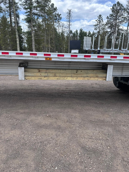 Pair of aluminum trailer dunnage carriers installed along a flatbed trailer with lumber