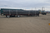 Adjustable aluminum flatbed bunks with vertical stake supports securing large diameter industrial pipe on a heavy-duty flatbed trailer in a jobsite yard.