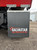 Galvanized swinging mud flap hanger bracket kit with quick link mounting installed on a dump truck, allowing flexible mud flap movement.
