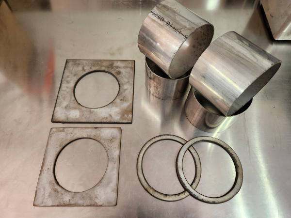 Stainless steel 5in-to-4in reducer adapter with hardware, used for adapting 4" exhaust systems to fit 5" heat kit diverter box and spring plate.