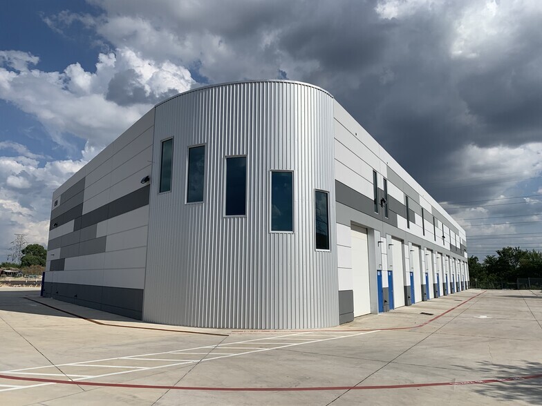 Exterior view of a large warehouse building with a modern design, featuring a spacious parking lot and well-maintained landscaping.