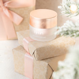 Golden Cream Rejuvenating Glow Cream sitting on top of wrapped presents. 