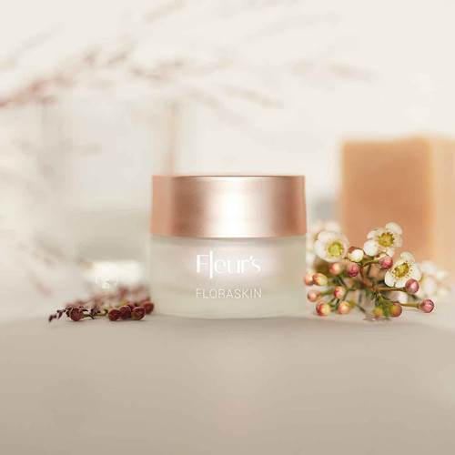 A glass jar of Fleur's Floraskin cream with a rose gold lid, surrounded by delicate flowers and soft lighting. A glass jar of Fleur's Floraskin cream with a rose gold lid, surrounded by delicate flowers and soft lighting.