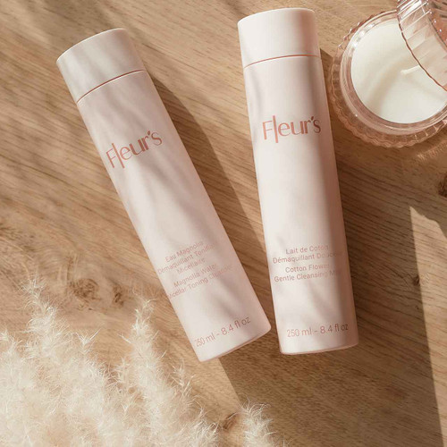 Two skincare bottles from Fleur's, labeled as a micellar toning cleanser and a gentle cleansing milk, on a wooden surface.