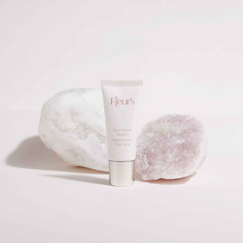 A tube of eye care cream is placed between two smooth, light-colored stones on a soft background. A tube of eye care cream is placed between two smooth, light-colored stones on a soft background.