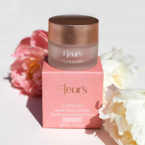 A jar of Fleur's Florallove vitamin-enriched floral cream sits atop a pink box, surrounded by soft floral accents.