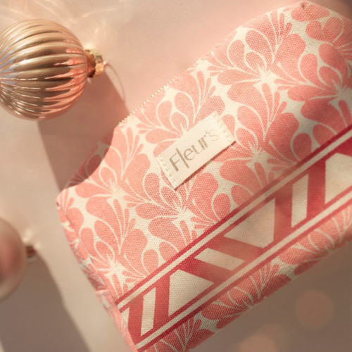 A Fleur's branded gift bag with pink floral pattern sits beside a decorative rose gold ornament.