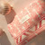 A Fleur's branded gift bag with pink floral pattern sits beside a decorative rose gold ornament.