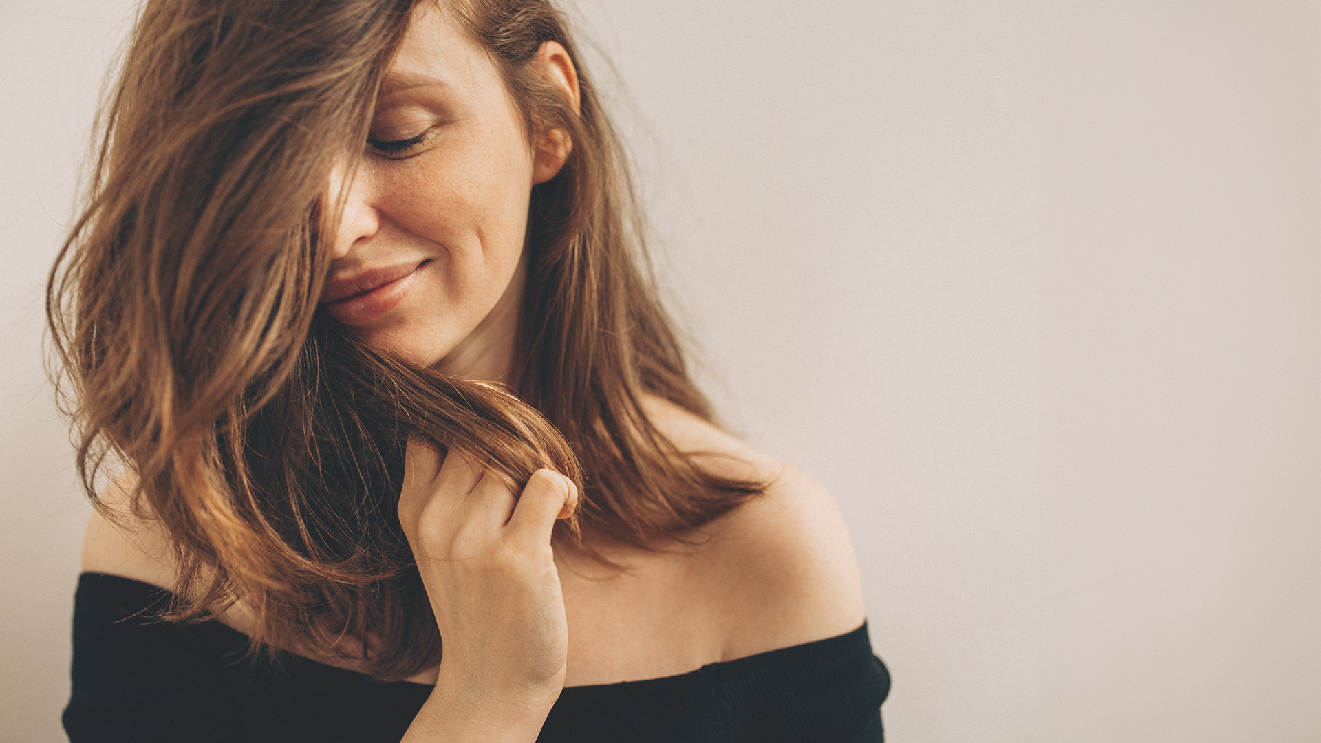 Woman gazing down with her fingers in her hair.