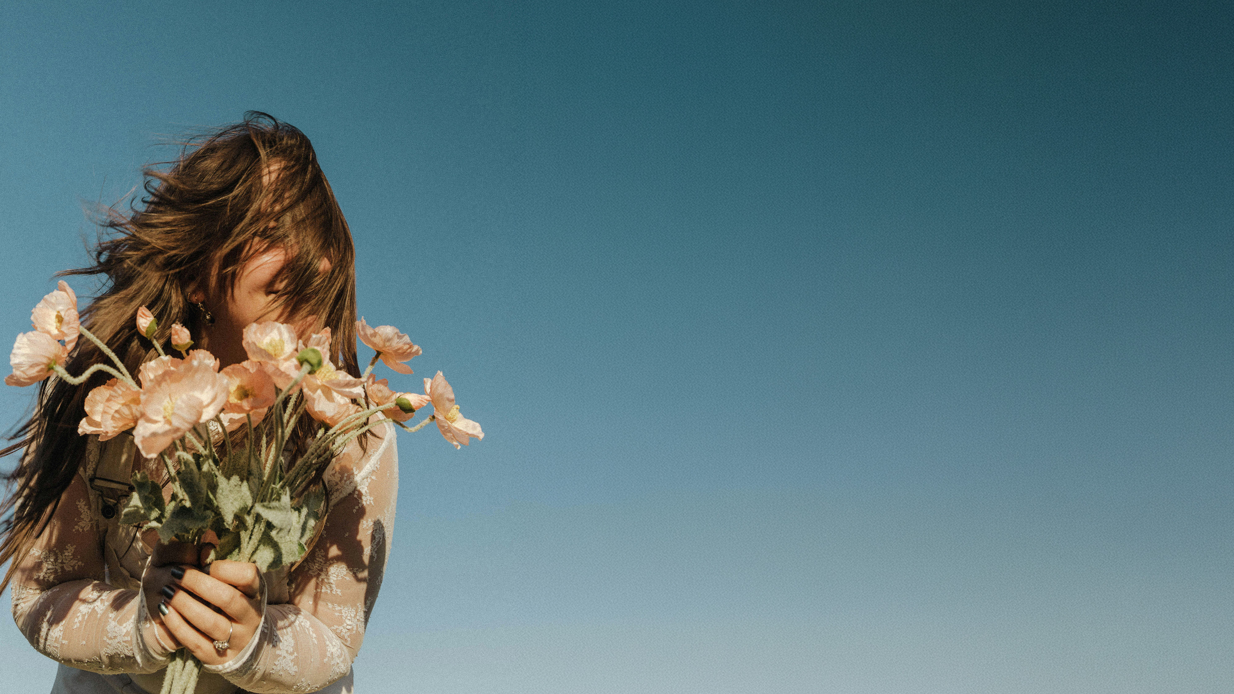 Woman holding a bushel of flowers to her chest.
