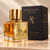 Unified Theory Extrait de Parfum in a gold-capped glass bottle beside its black presentation box with gold Alchemy & Aura branding and the words Where Scent Transforms the Soul.