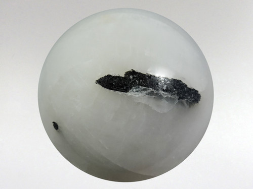 Amazing white quartz sphere with rods of black tourmaline inclusions.