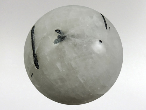 Stunning white quartz sphere with rods of black tourmaline inclusions.