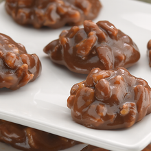 Close-up of glossy, caramelized Lammes Candies Texas Chewie Pecan Pralines on a white plate, showcasing their rich, nutty texture.